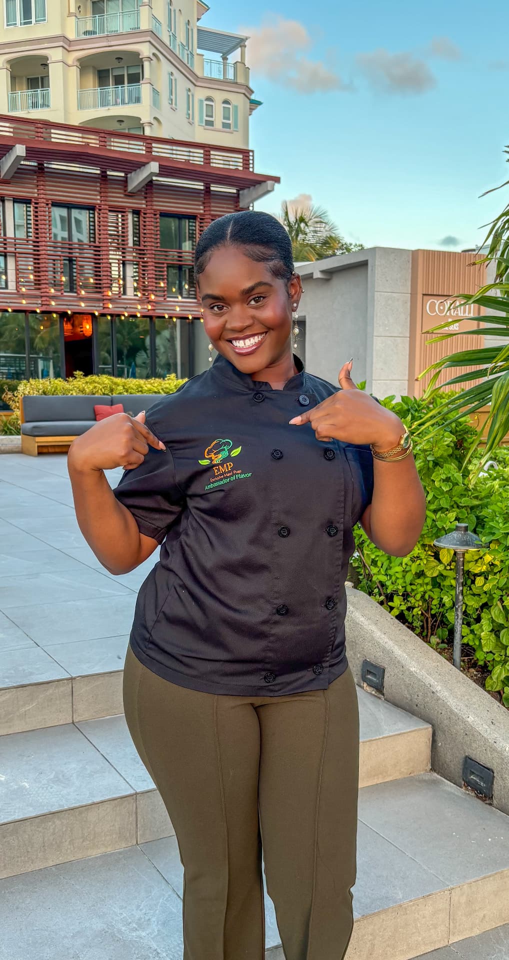 The Ambassador of Flavor smiling and pointing to the EMP logo on her chef jacket
